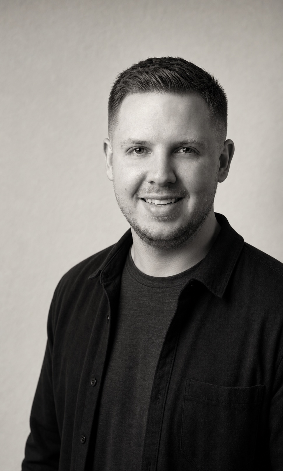 Jacob Crandall in a casual dark overshirt, smiling against a light background